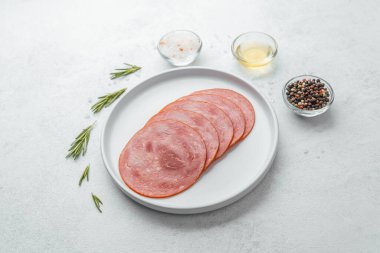 Beyaz tabakta dilimlenmiş sosis ve baharat.