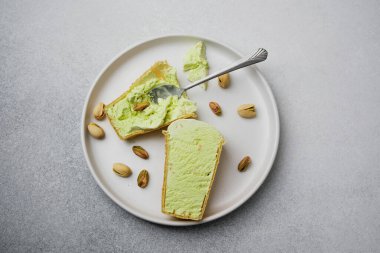 Fıstıklı dondurma külahları beyaz bir tabakta dağınık fındıklı, bir kaşıkta tek koni.