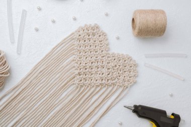 Beyaz arka planda tutkal tabancası ve kablosu olan kalp makromu.