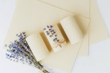 Pastel arka planda lavanta demeti olan üç balmumu mum.