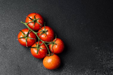 Koyu bir arka planda altı olgun vişne domatesi, canlı tazeliklerini sergiliyorlar..