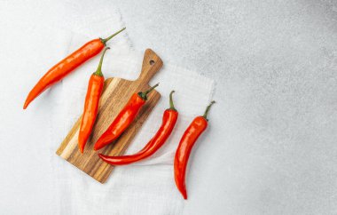 Taze kırmızı biberler ahşap bir kesme tahtasının üzerine serilmişti..