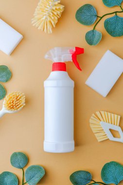 Beyaz temizlik spreyi şişesi, yeşil yapraklı şeftali arkaplanda fırçalar ve süngerler.