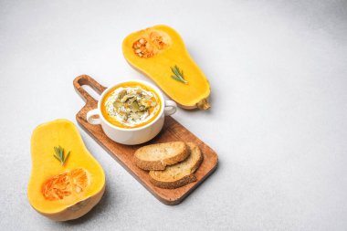Ahşap bir tahtanın üzerinde kabak çorbası ve ekmek, doğal.