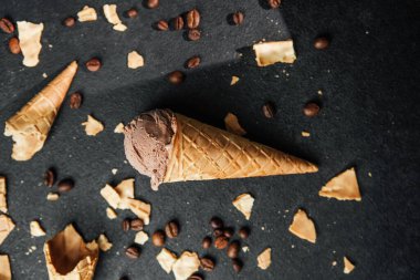 Kahveli dondurma külahı ve siyah arka planda waffle kırıntıları.