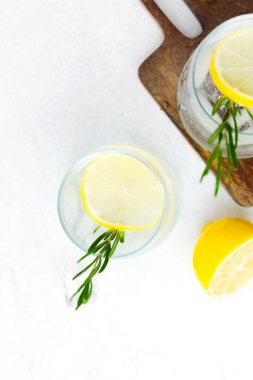 Limon kokteylini biberiye ve buz küpleriyle tazeleyip beyaz arka planda beyaz ahşap tahtada servis ediyorum.