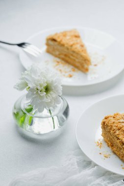 Napoleon millefeuille tatlı kremalı pasta beyaz tabaklarda çiçek detaylarıyla servis edilir.