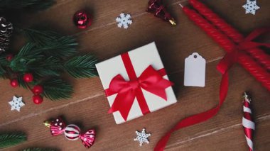 Kırmızı kurdele, çam dalları, mumlar ve ahşap süslerle Noel hediyesi hazırlığı