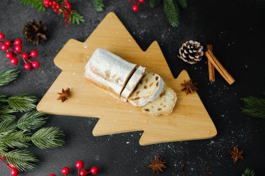 Noel pastası ağaç tahtasında şekerle tozlanmış böğürtlen, kozalak ve tarçın çubukları