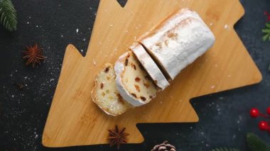 Tahta kesme tahtasının üzerinde toz şekere bulanmış tatlı ekmek ve kış süslemeleri.