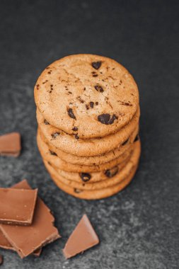Taze pişmiş kurabiyeler üst üste yığılmış çikolata parçalarının yanında eğlenmeye hazır..