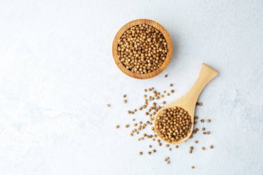 Beyaz arka planda kişniş tohumlu ahşap kase ve kaşık