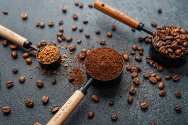 Ground Coffee ve gri arka planda kepçeli fasulyeler.