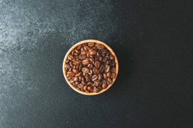 Koyu arkaplanda, tahta kasede kahve çekirdekleri.