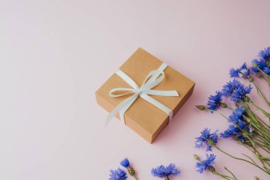 Pembe arka planda hediye kutusu ve çiçek.