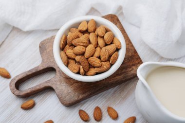 Tahtada süt sürahisi olan organik bademler, sağlıklı vejetaryen içeceği hazırlığı.
