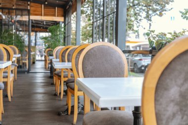 Ahşap sandalyeleri ve konukseverlik ve yemek konsepti için beyaz masaları olan zarif bir kafe.