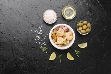 Minimalist gurme ya da malzeme tasarımı konsepti için siyah masa üzerinde limon ve şifalı deniz ürünleri kasesi.