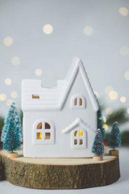 Küçük, beyaz bir ev, içinde sıcak bir ışık var. Etrafı hep yeşil ağaçlarla çevrili.