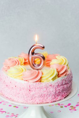Pembe ve sarı kremayla süslenmiş canlı bir doğum günü pastası altıncı yaş gününü kutluyor..
