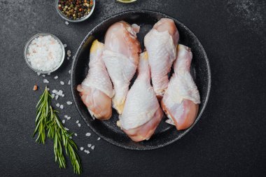 Siyah kasede çiğ tavuk budu ve baharat.