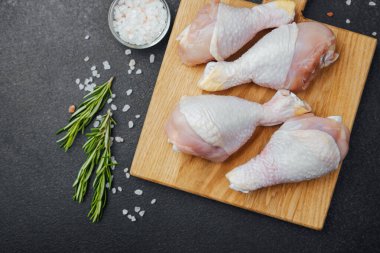 Ahşap tahtada çiğ tavuk budu ve baharat.