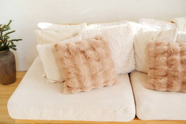 Rahat yumuşak yastıklar ve kanepesinde yeşil dallar olan bir vazo.