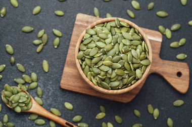 Tahta kasede kabak çekirdeği ve arka planda kaşık.