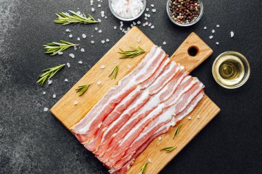 Siyah yüzeyde baharat ve biberiye ile sıralanmış jambon dilimleri.