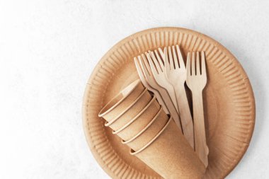 Tek kullanımlık plaka üzerine eko kağıt bardak ve çatallar beyaz arkaplan düzlüğü üzerine kurulur