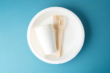 Çevre dostu tabaklarda beyaz kağıt bardaklar ve ahşap çatallar.