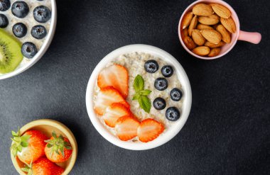 Çilekli ve yaban mersinli yulaf ezmesi kasesi. Nane arkaplanlı.