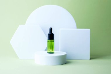 Dairesel kaide üzerinde siyah kapaklı yeşil kozmetik damlası şişesi