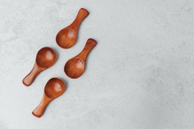 Dört iyi işlenmiş tahta kaşık pürüzsüz bir ışık yüzeyinde sergilenir..