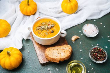 Kabuklu ekmek, taze tohum ve kırsal bir masada servis edilen baharatlı balkabağı çorbası..