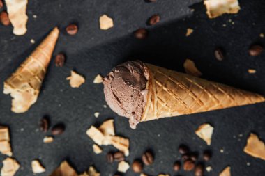 Kahveli dondurma külahı ve siyah arka planda waffle kırıntıları.