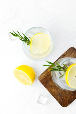 Limon kokteylini biberiye ve buz küpleriyle tazeleyip beyaz arka planda beyaz ahşap tahtada servis ediyorum.