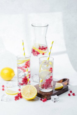 Limon dilimleri ve sarı çizgili kamışlarla servis edilen kırmızı meyveli içecek.