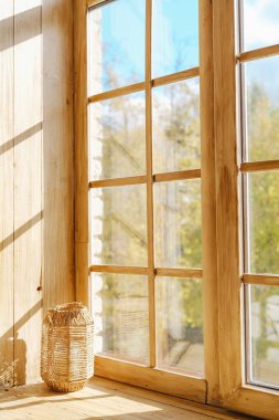 Ilık güneş ışığı ahşap bir pencereden içeri akar, pervazdaki dokuma sepeti aydınlatır..