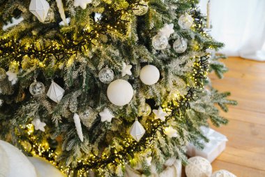 Beyaz süslemeler ve sıcak ışıklarla dekore edilmiş sonsuz yeşil ağaç.