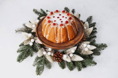 Beyaz kremalı, kırmızı böğürtlenli, yeşil dallı, kozalaklı bayram pastası..