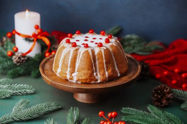 Beyaz kremalı, ahşap tezgahta kırmızı böğürtlenli, yanan bir mumla nefis bir kek..