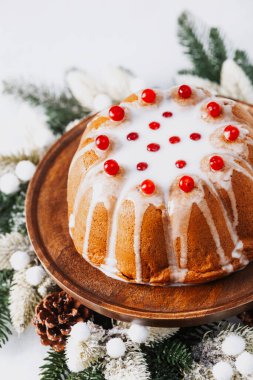 Beyaz kremalı, kırmızı böğürtlenli kutlama pastası. Tahta tezgahta tatil tatlısı, çam ağacı dekoru..
