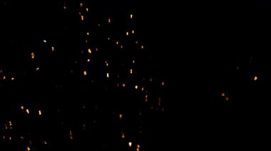 Işıl ışıl parlayan altın közler. Karanlık bir arka planda parıldıyor. Yumuşak, sıcak bir ışık yaratıyor.