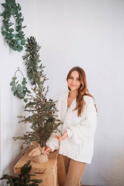 Kadınlar okaliptüs çelenklerinin yakınındaki ahşap bir masaya meyvelerle süslenmiş küçük yeşil ağaçları yerleştirirler.