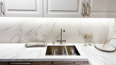 Modern mutfak beyaz mermer tezgah lavabo musluğu ve zarif gümüş detaylar