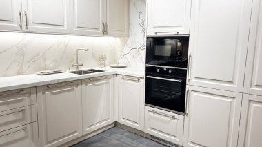 Modern beyaz mutfak, dolaplar, mermer tezgah ve entegre aletler..