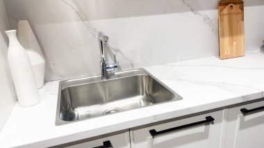 Parlak modern mutfak paslanmaz çelik lavabo, beyaz mermer tezgah, zarif dekorasyon, temiz iç mekan..