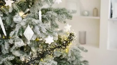 Beyaz süslemeleri ve peri ışıklarıyla süslenmiş ebedi yeşil ağaç, bayram mevsimi.