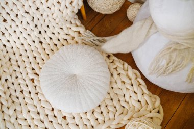Tombul örgü krema battaniyesi, ahşap zeminde yumuşak yastık, yumuşak dokular.